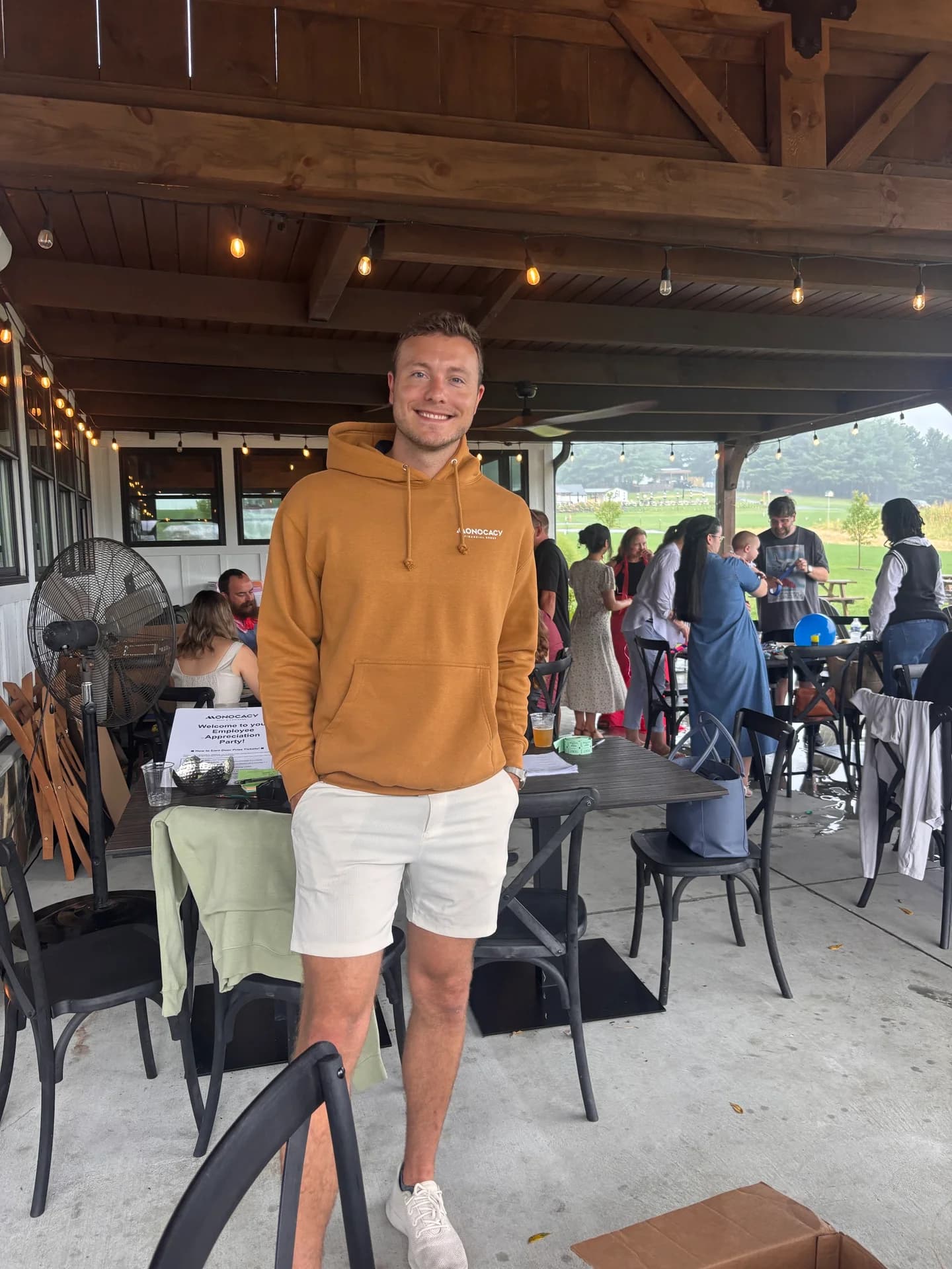 Carter Shaffer smiling in an orange Monocacy hoodie on a covered patio.