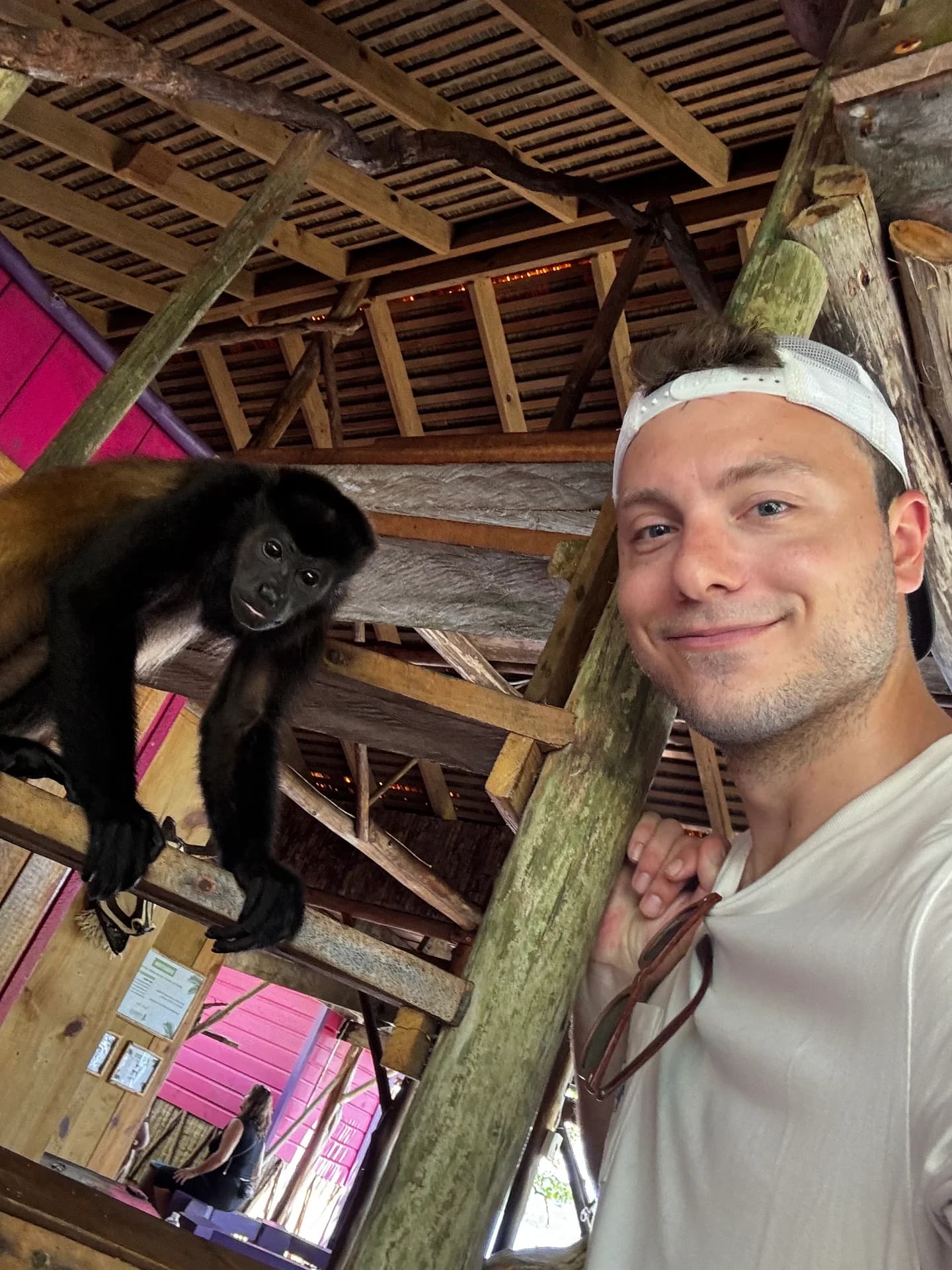 Carter Shaffer taking a selfie beside a monkey perched on a wooden railing.